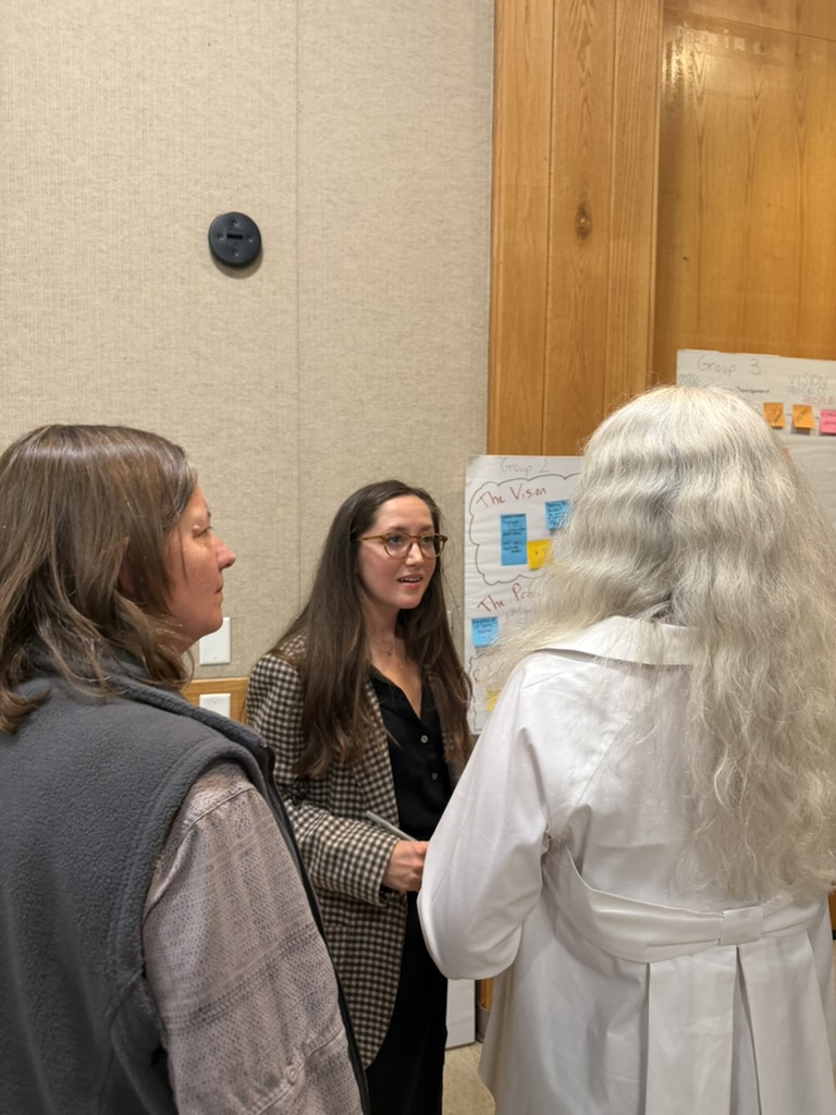 Attendees in conversation beside a vision poster from a working group